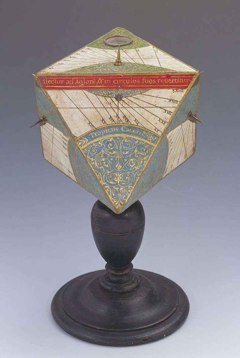 A polyhedral wooden sundial with an octagonal head (regular octahedron) and a turned wooden pedestal, featuring a compass on the top surface and decorative gold foliate motifs.
