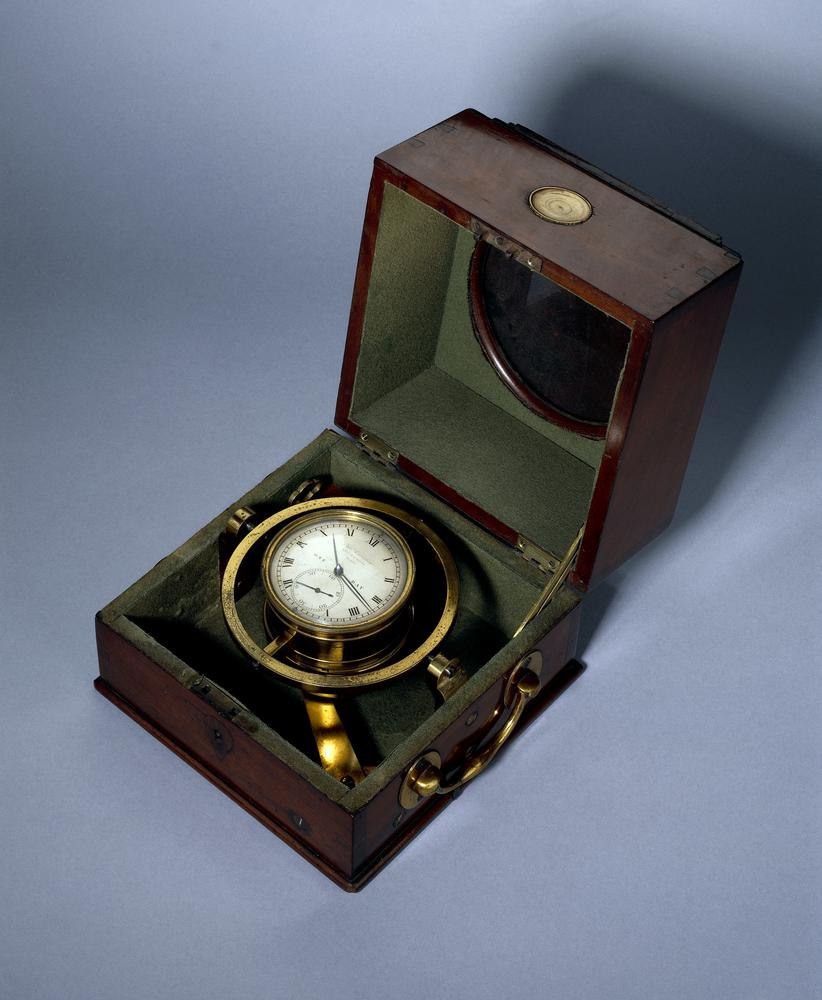 Three-quarter view of the Thomas Earnshaw marine chronometer in its gimballed brass bowl within the opened mahogany box