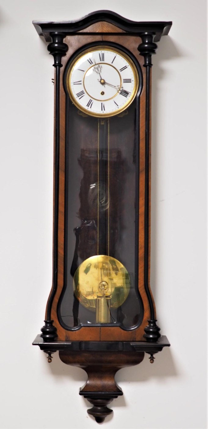 Full view of the wall regulator clock, showcasing the glazed door, walnut veneer case, and internal pendulum.