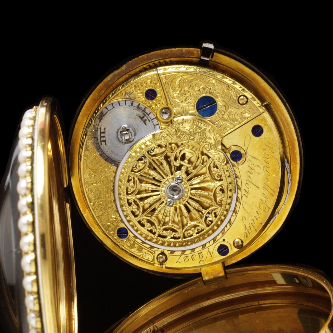 Full view of the pocket watch showing the white enamel dial, Arabic numerals, and the pearl-set bezel.