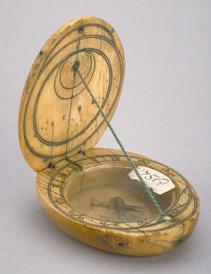 Diptych dial made of bone showing the open leaves, the string gnomon, and the compass bowl.