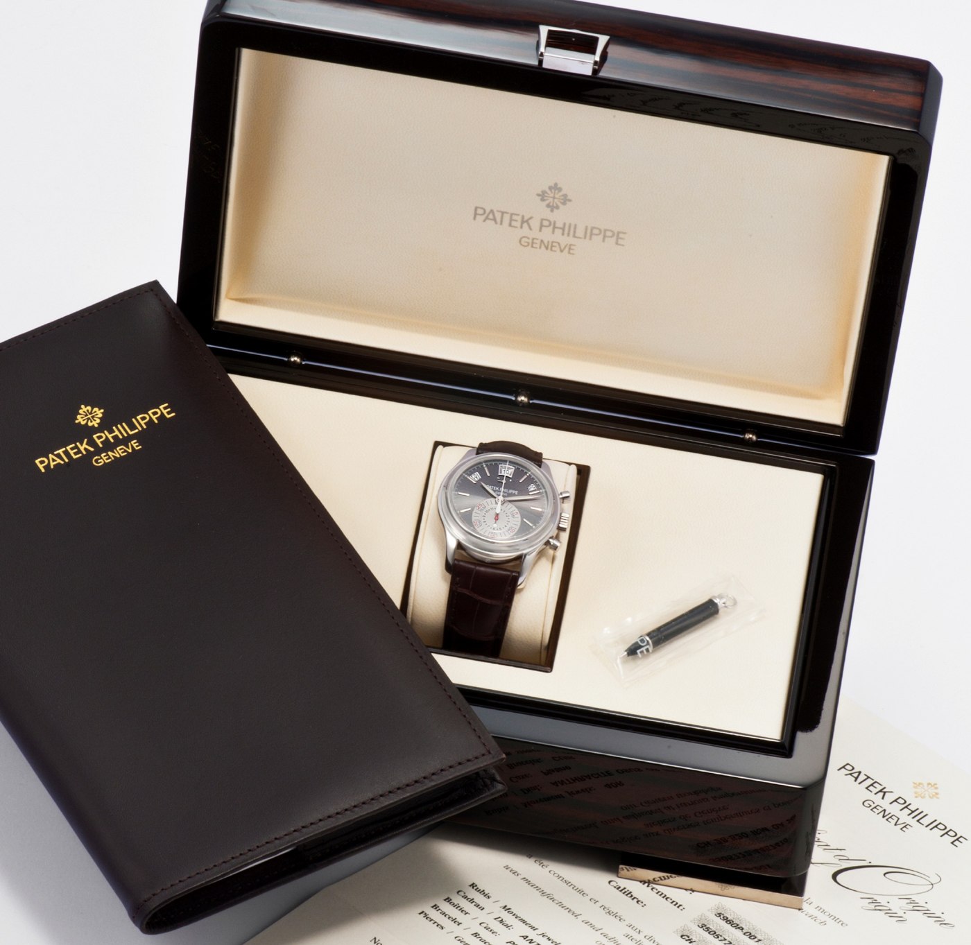 The Patek Philippe Ref. 5960P wristwatch displayed within its fitted box, including the Certificate of Origin and setting pin.