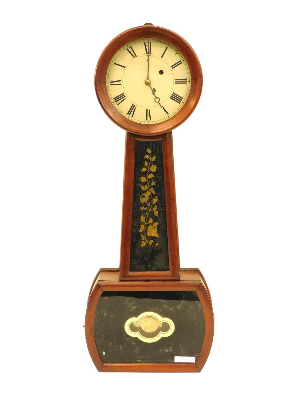 A frontal view of the banjo clock displaying the iron dial, gilt-painted throat and base tablets, and mahogany frame.