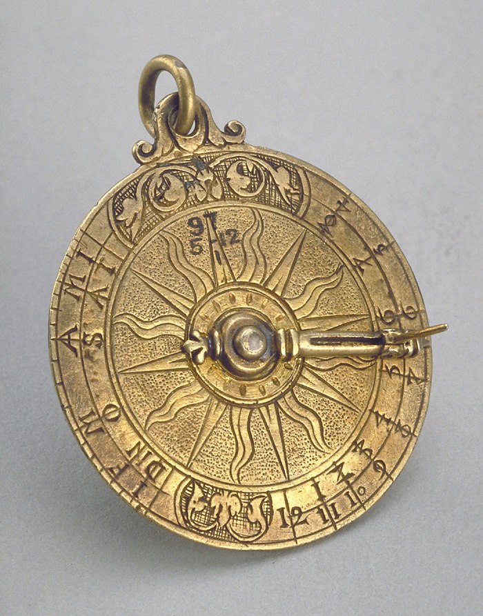 Vertical disc dial showing the front face with alidade, folding gnomon, sun motif, and engraved time/month scales.