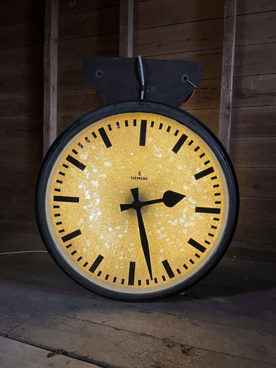 Front view of illuminated Siemens industrial clock with overhead bracket
