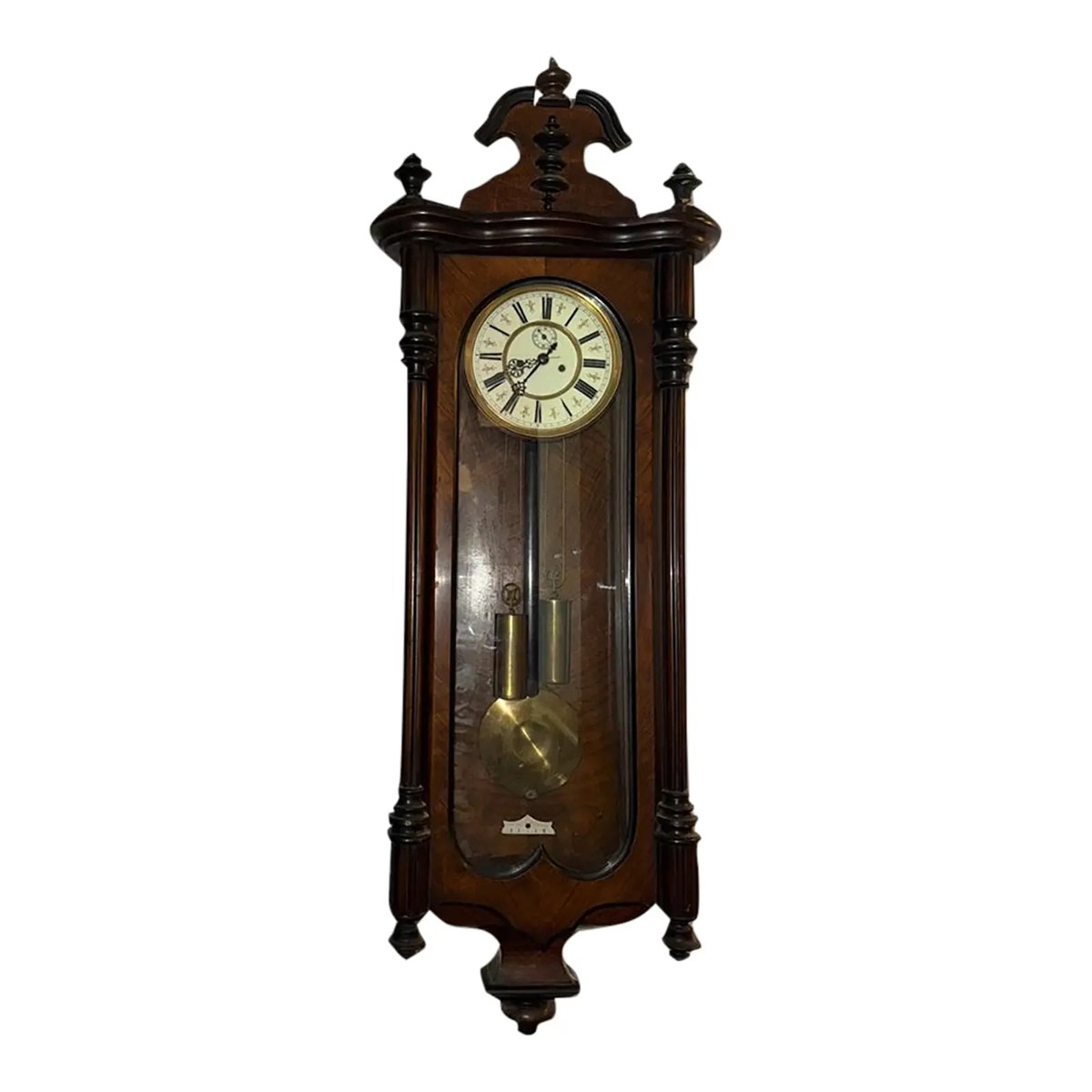 Frontal view of the carved wooden Vienna regulator wall clock showing dial, weights, and pendulum