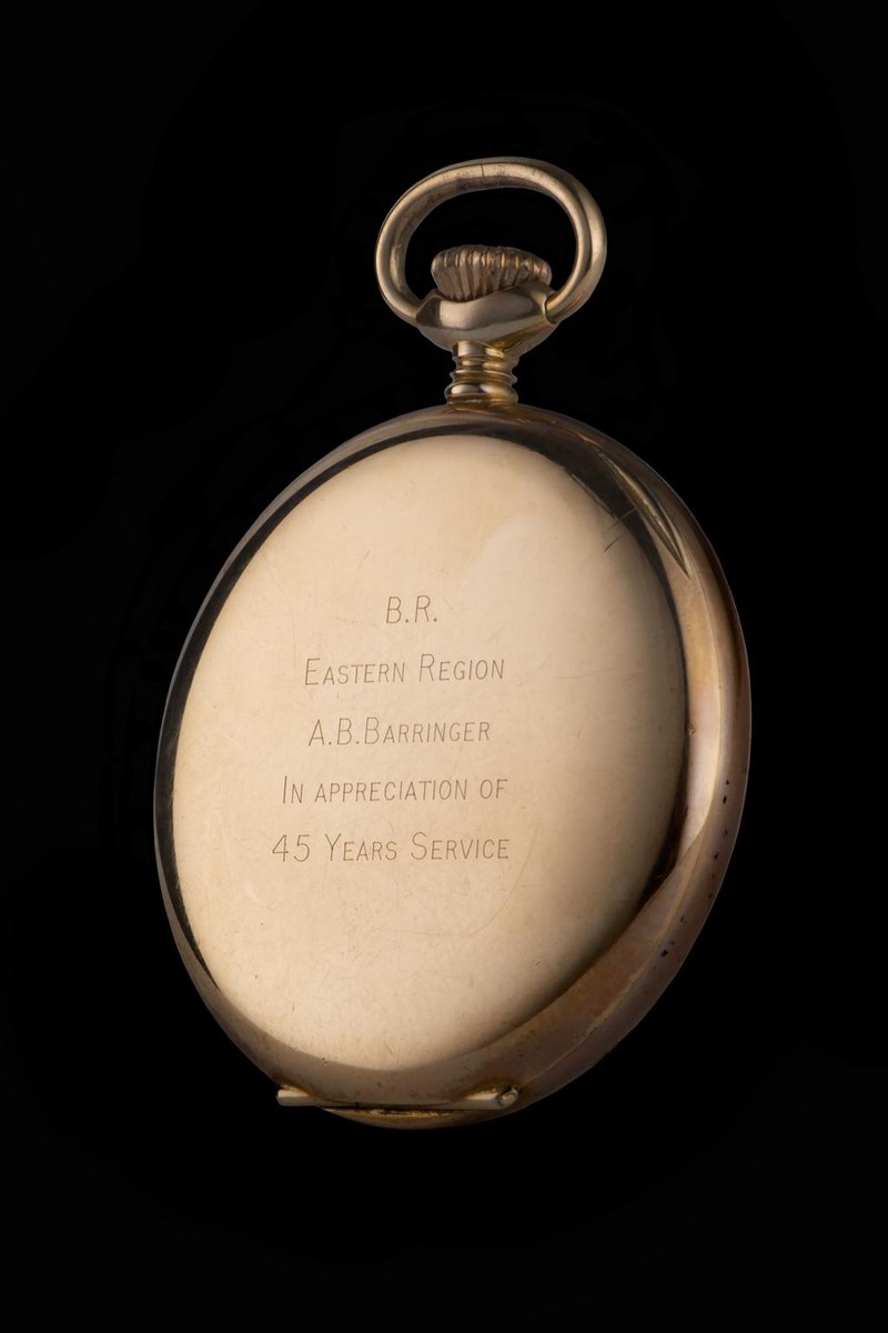 Rear three-quarter view showing the engraved presentation case back, winding crown, and bow