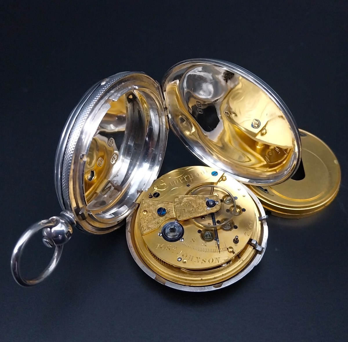 Open silver case displaying the gilt full-plate movement and separate dust cover