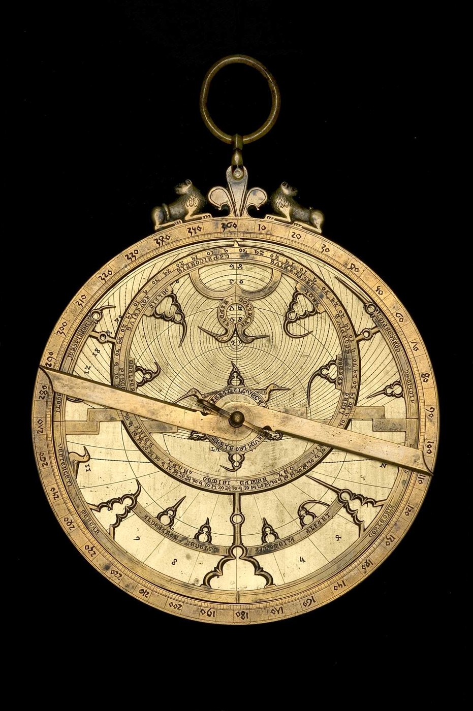 Front view of the brass astrolabe showing the rete, throne with lion motifs, and rule.