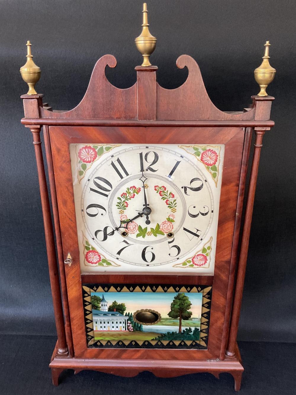Front view of the 1820s Samuel & Eli Terry pillar and scroll clock showing the dial, reverse glass painting, and brass finials.