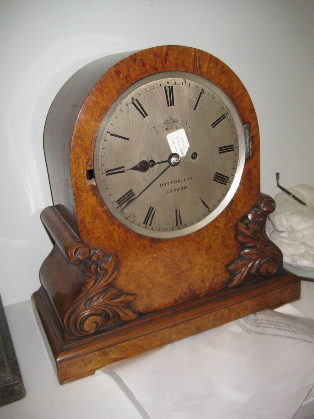 Front view of the Dutton & Co. table clock showing the silvered dial, VR cipher, and burr walnut case.
