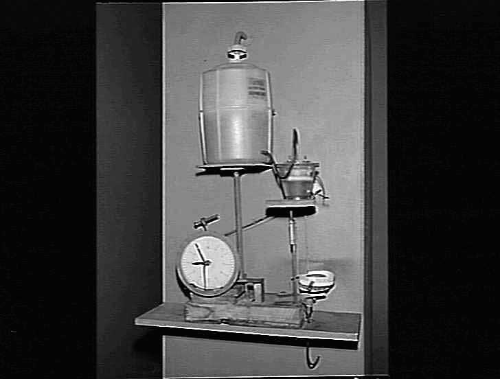 Full view of the water clock, showing the water reservoir, horizontal pendulum, and the gear train mounted on a central stand.