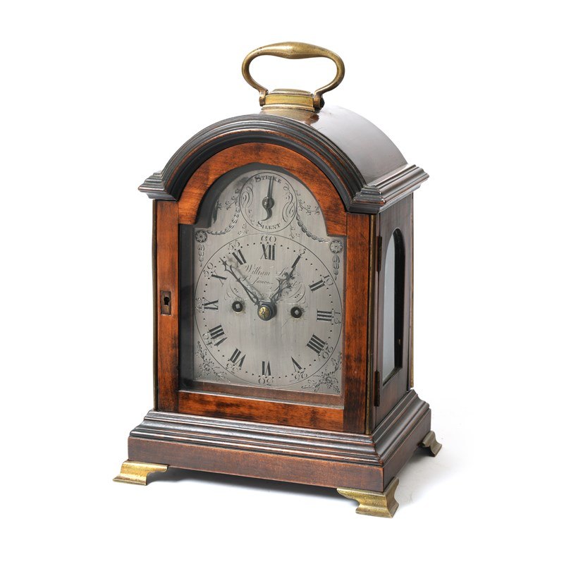 Three-quarter front view of the George III mahogany mantel clock with silvered dial, lot 502