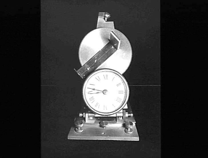 A profile view of the brass sunclock showing the adjustable arm and gear assembly.