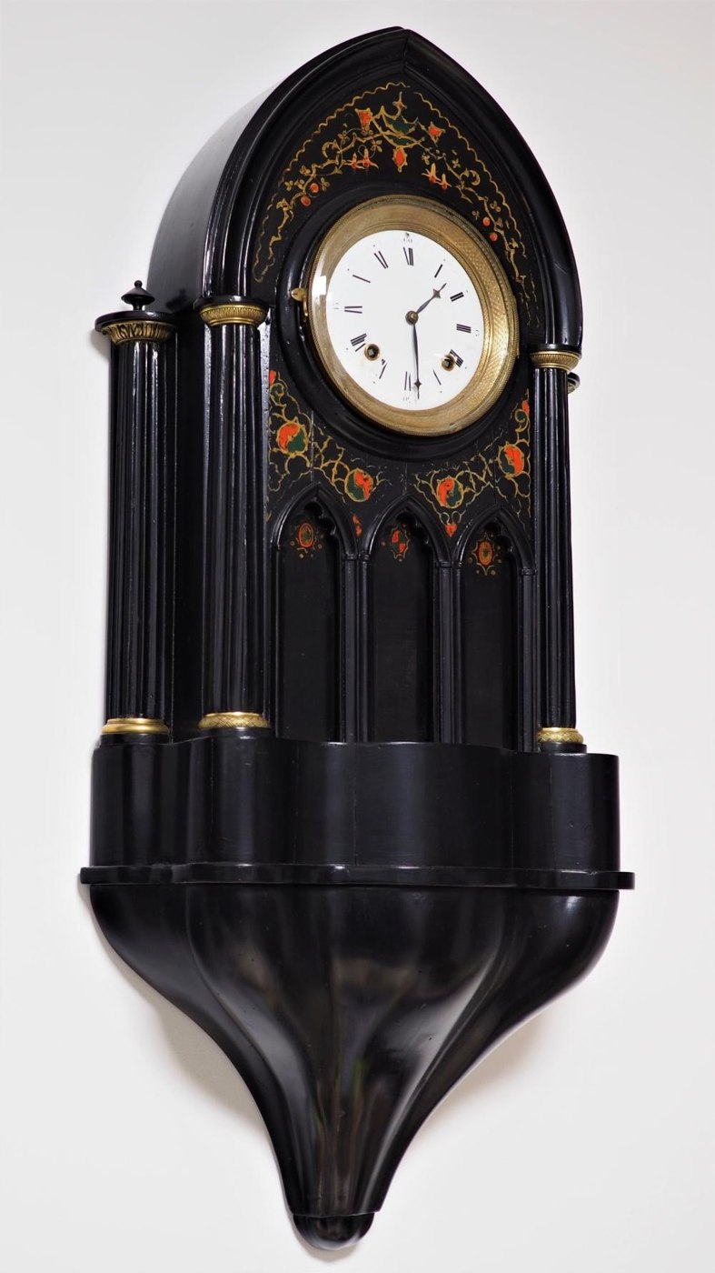 Front view of the blackened wooden Viennese cathedral clock with floral decoration and gothic-style architectural features.
