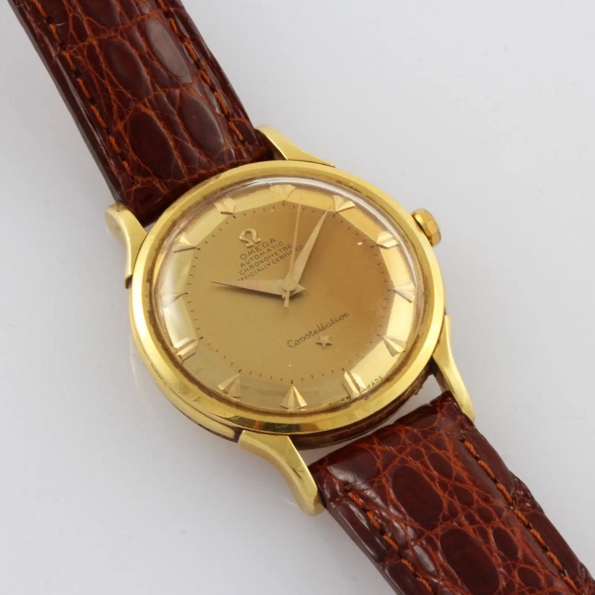 Oblique view of the Omega Constellation ref. 2700 SC showing the 18K yellow gold case, gold pie-pan dial, and leather strap