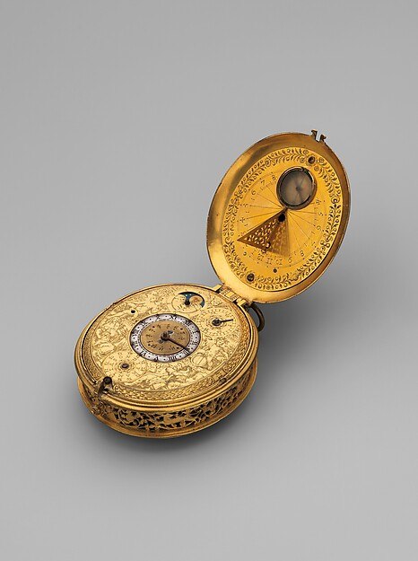 The open clock watch displaying the dial and the interior cover with its folding sundial.