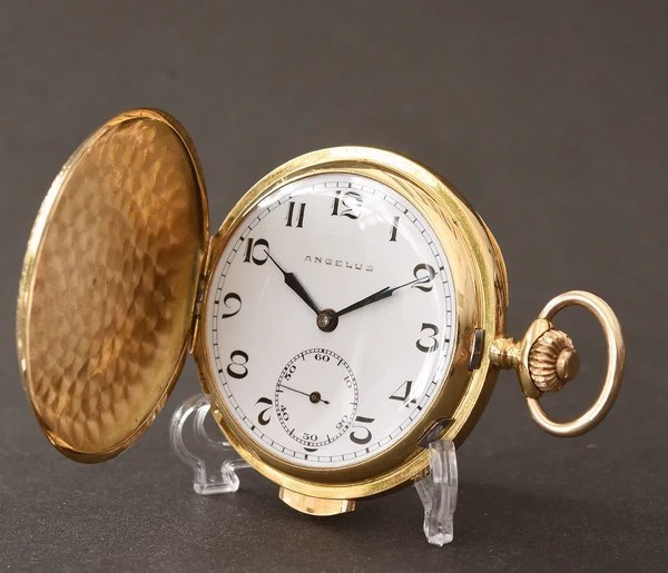 Front three-quarter view showing the opened hunter cover, enamel dial, and side repeater slide of the 18K gold Angelus pocket watch
