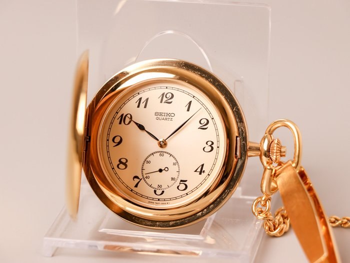 Front view of open gold-tone Seiko full hunter pocket watch displaying champagne dial and attached chain