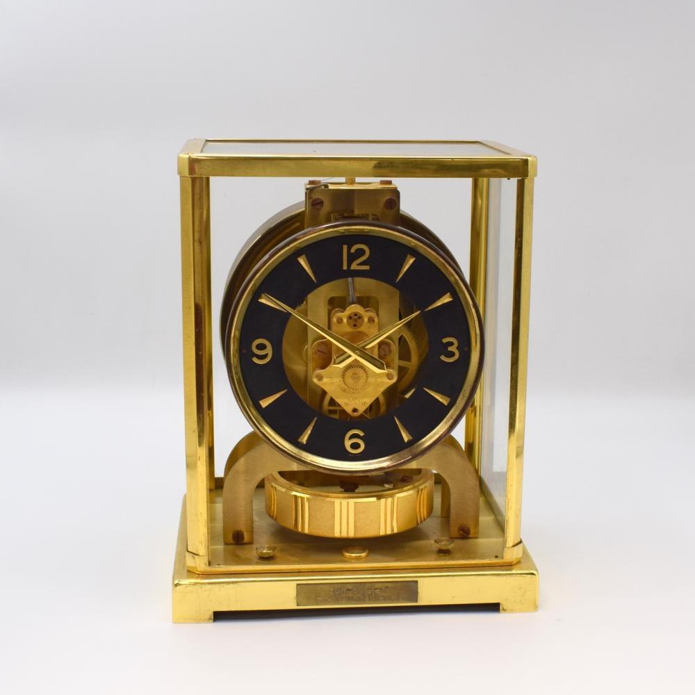The gold-plated LeCoultre Atmos clock viewed from the front, showing the black ring dial, glazed case, and the internal movement and pendulum.