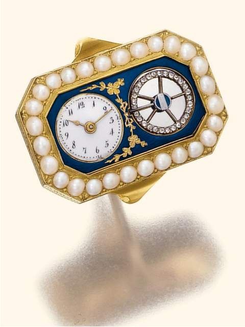An 18K gold octagonal ring watch with pearl-set bezel, featuring a translucent blue enamel dial plate with gold laurel branches, an Arabic numeral dial, and an aperture for the diamond-set balance.