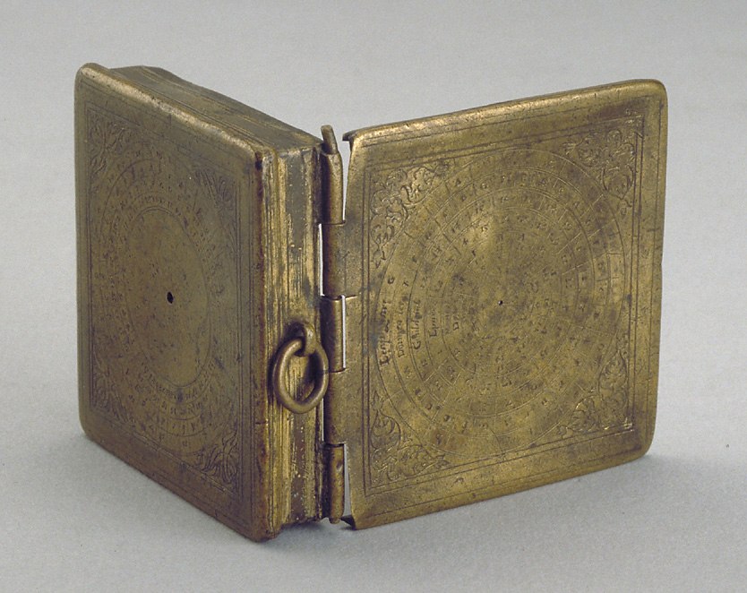 View of the open gilt brass case showing the engraved concentric calculation rings on the lid and box base.