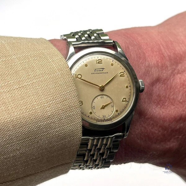 Dial view of the Tissot Antimagnetique wristwatch on the wrist showing gilt numerals, leaf hands, and sub-seconds dial