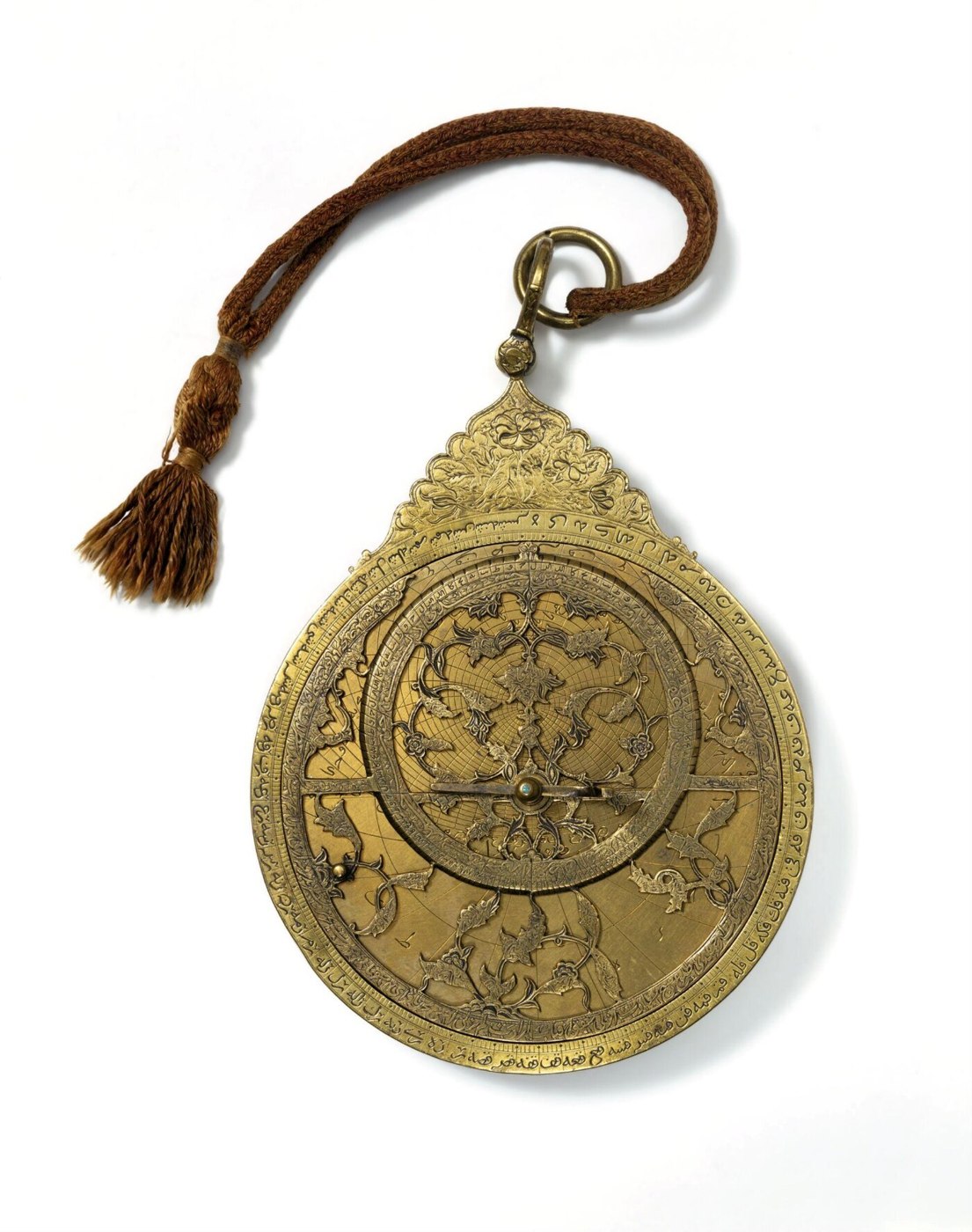 Front view of the brass astrolabe showing the rete, alidade, and the calligraphic engraved rim.
