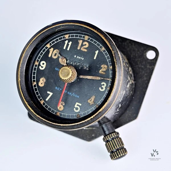 Front oblique view of Smiths Mk IIC 8-day aircraft dashboard clock showing dial, hands, central dummy-hand knob, and winding stem