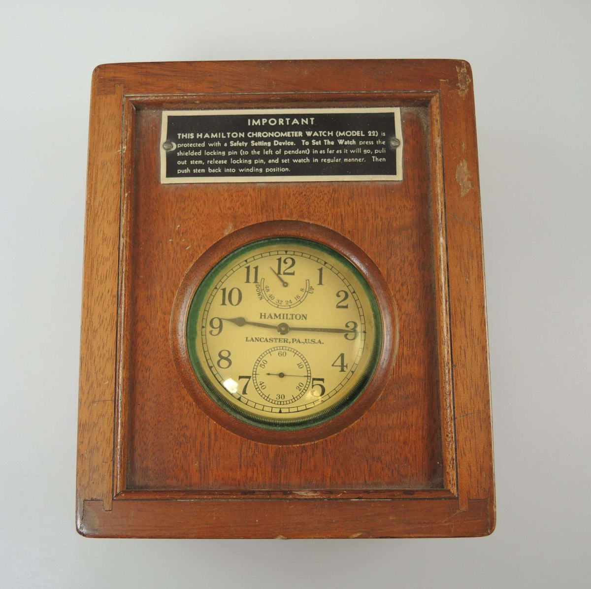 Top-down view of the Hamilton Model 22 deck watch enclosed inside its wooden deck box