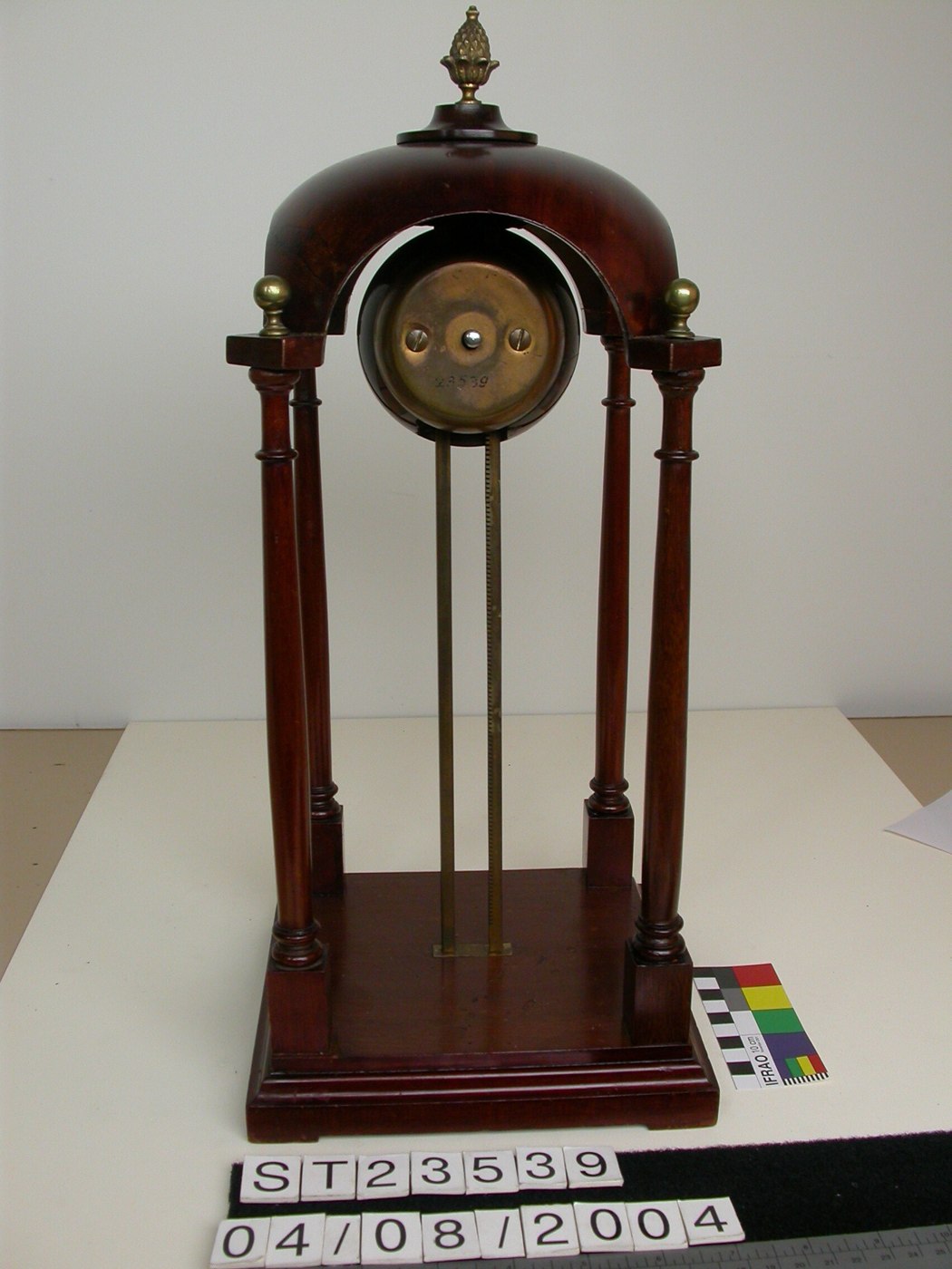 Gravity clock with a rounded body, wooden canopy and pillars, and a toothed vertical runner for gravity-driven descent.