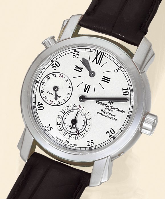Front view showing the regulator dial, pusher at the top left, and subsidiary registers for dual time and date.