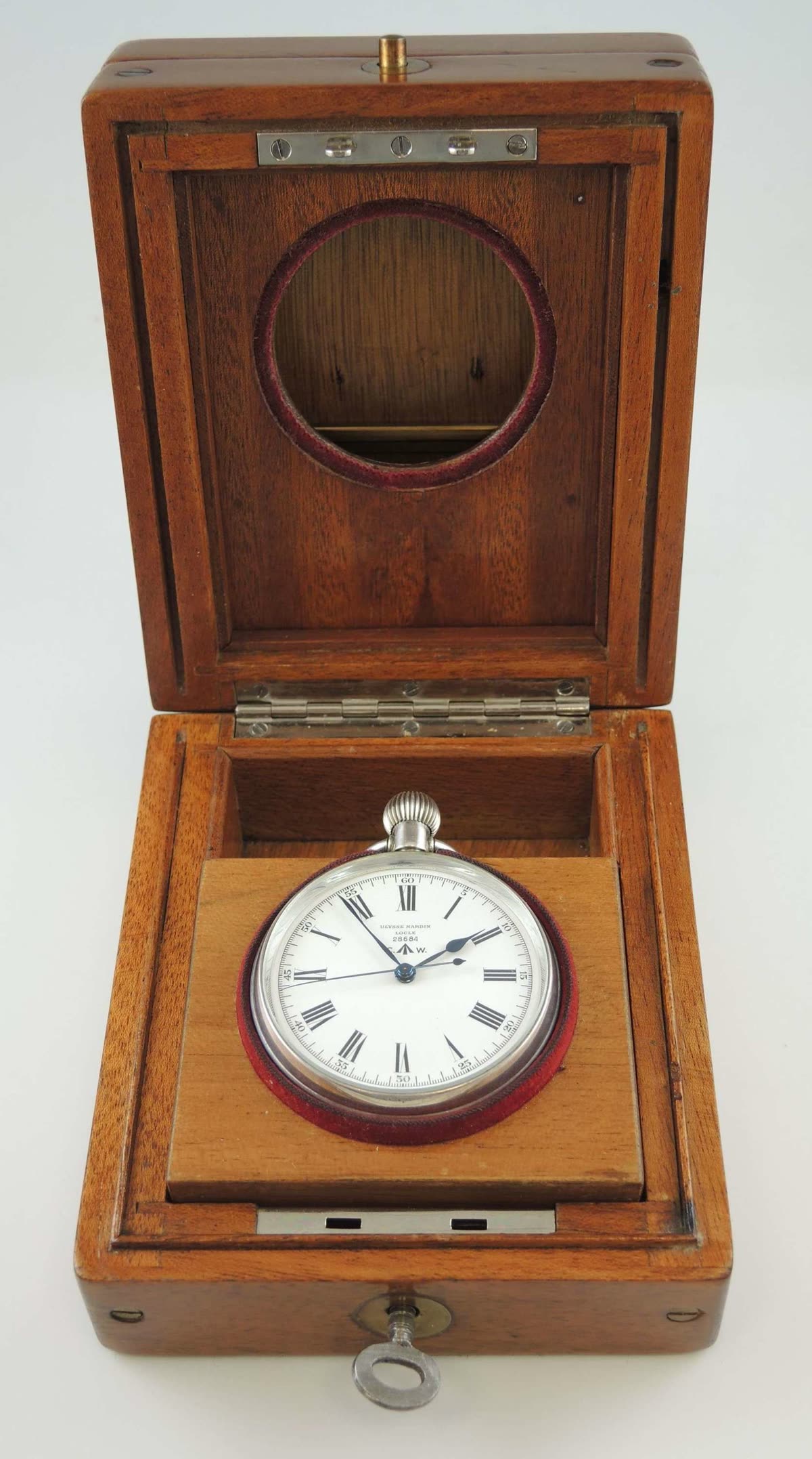 Front view of Ulysse Nardin deck watch seated inside its fitted wooden deck box with key