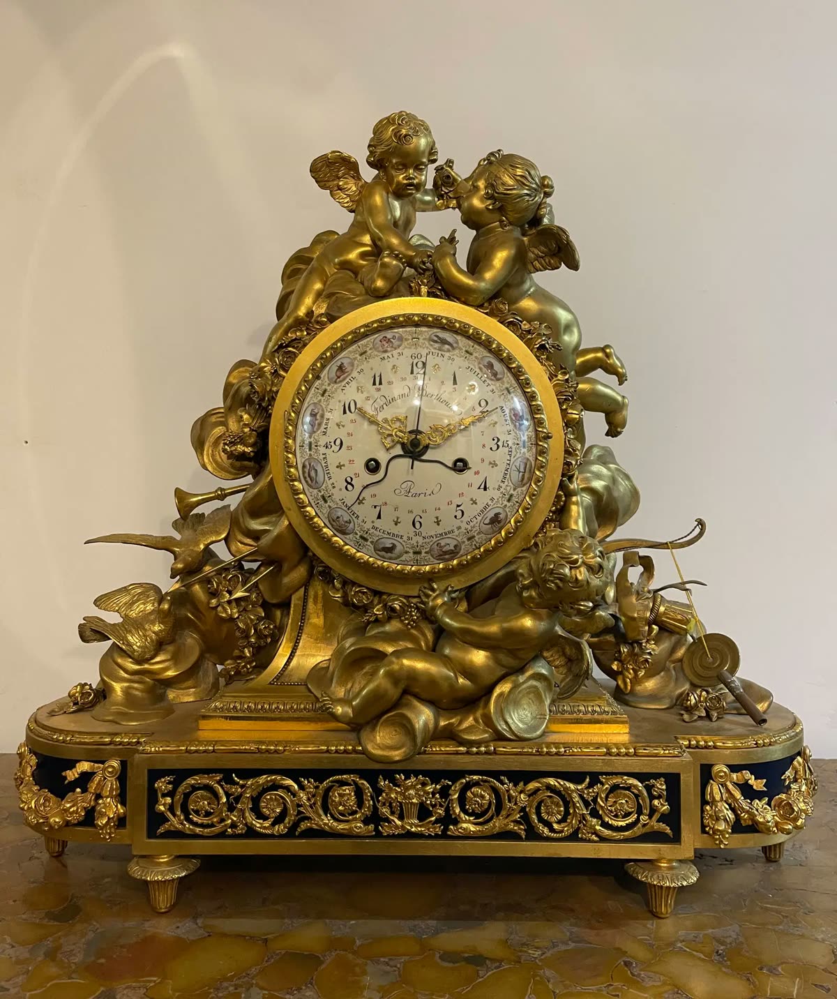 Front view of the French gilt bronze mantel clock with cherub mounts and calendar dial