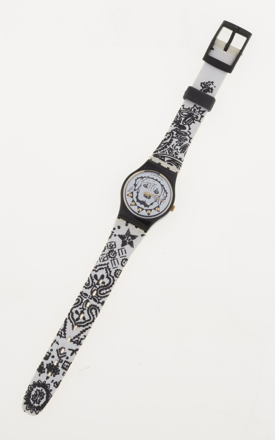 Front view of the Swatch 'Garage' wristwatch showing the black and white dog-face dial and patterned fabric strap.