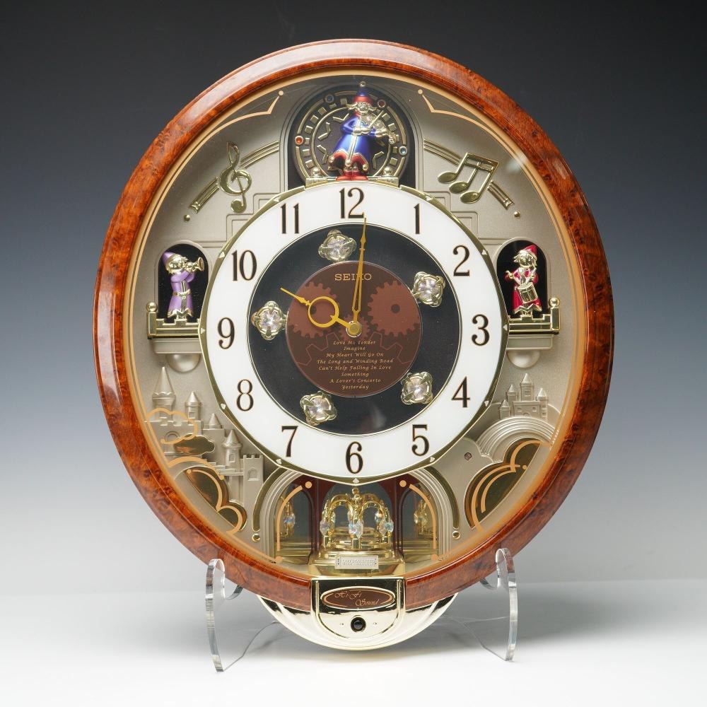 Front view of the Seiko Melodies in Motion wall clock showing the central dial, animated figures, and decorative Swarovski crystals.