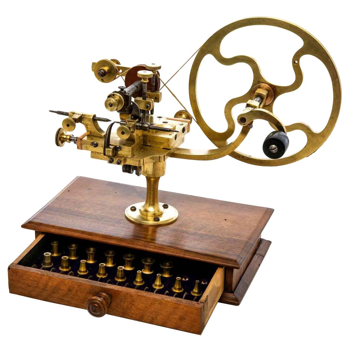 Elevated three-quarter view of the brass and steel rounding-up tool mounted on the walnut drawer base with collets displayed