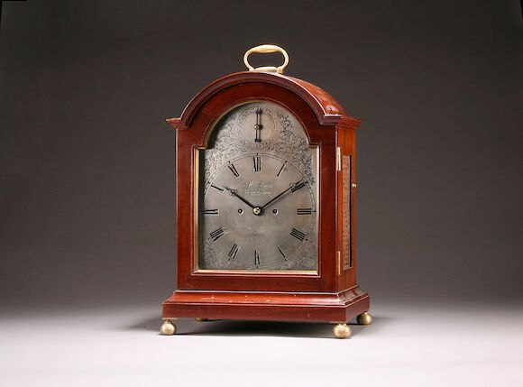 Front three-quarter view of the arched mahogany and rosewood bracket clock with silvered dial and brass carrying handle