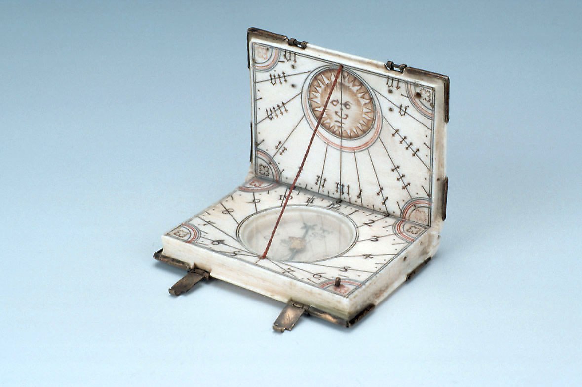 A diptych sundial in the form of a book, open to show internal dial faces and compass.