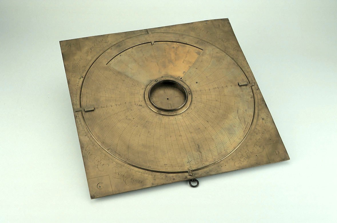 Square brass instrument showing the revolving disc, central compass bowl, and engraved scales.
