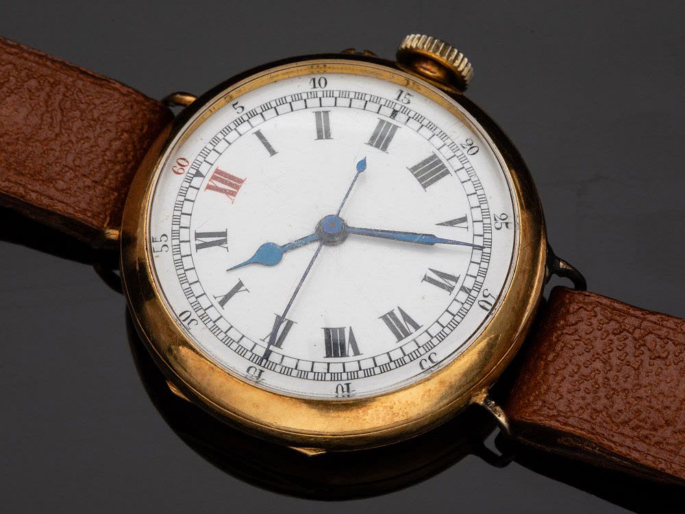 Front view of Stauffer, Son & Co. 18K gold wristwatch with white dial, red XII, and wire lugs