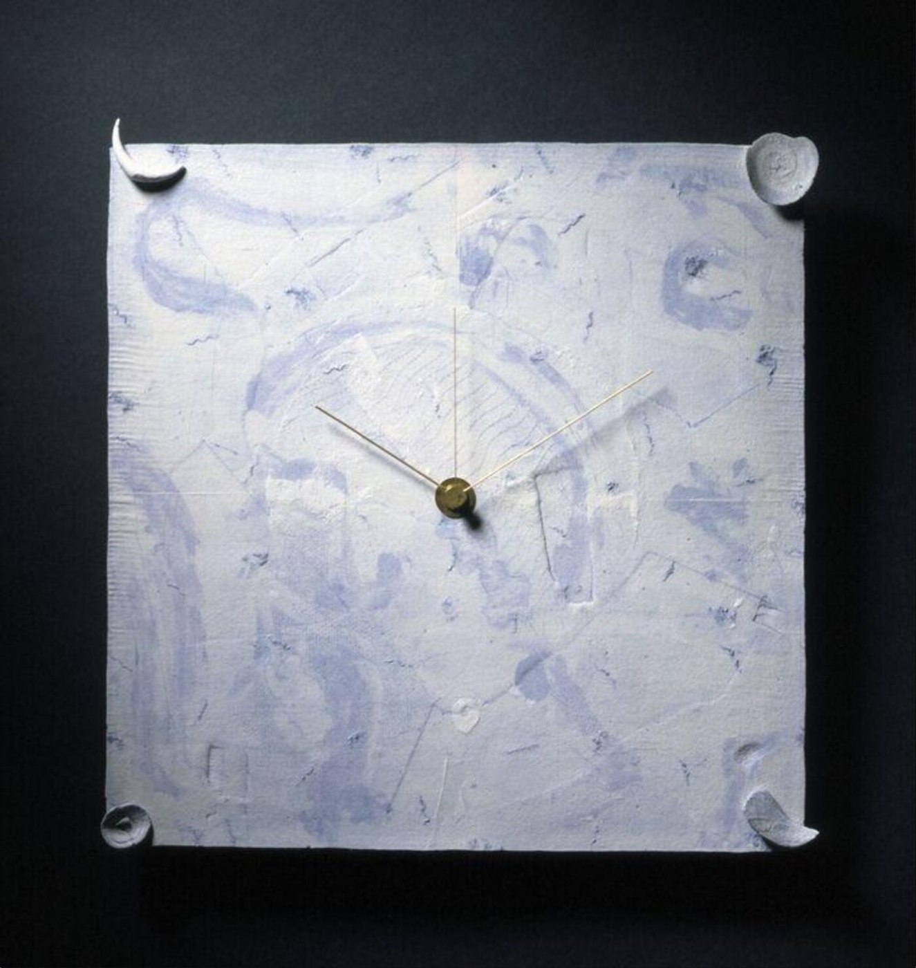 Front view of the 'IN ON TIME 4' wall clock, highlighting the square porcelain panel, hand-modelled corner elements, and brass hands.