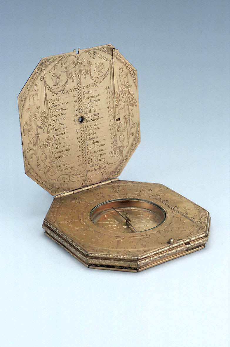 The gilt brass astronomical compendium showing the interior latitude table and the compass face.