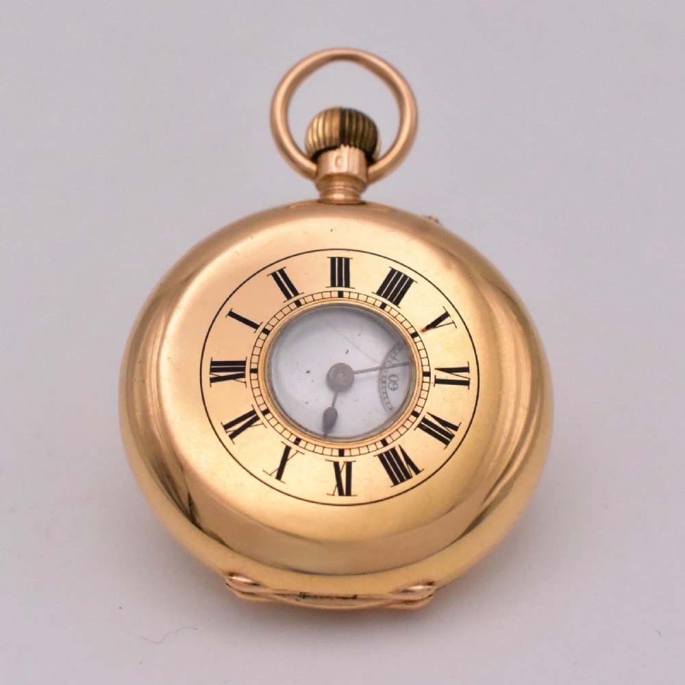 Front view of closed 18k gold half hunter pocket watch showing the case aperture and external Roman numerals