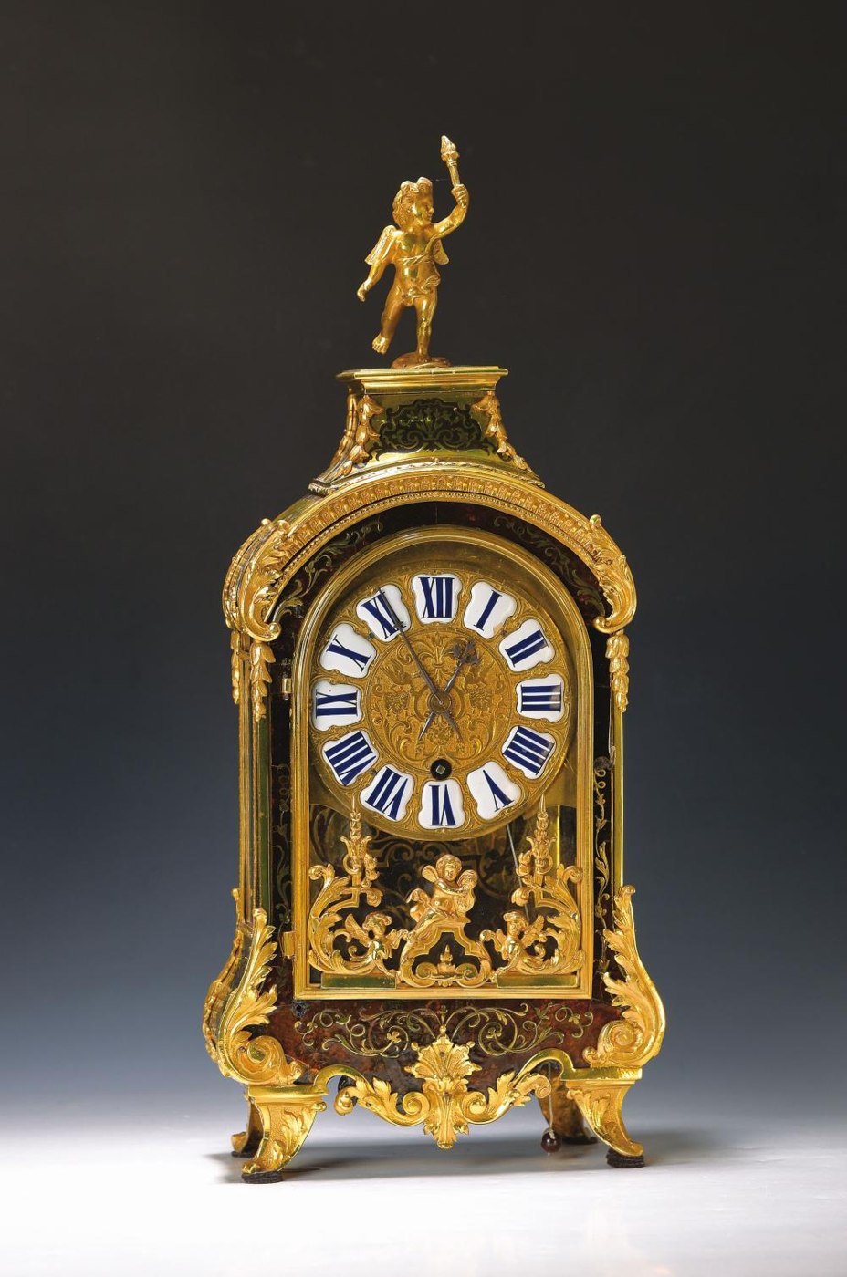 Boulle work pendule featuring a brass dial with enamel cartouches and a crowning putto figure.