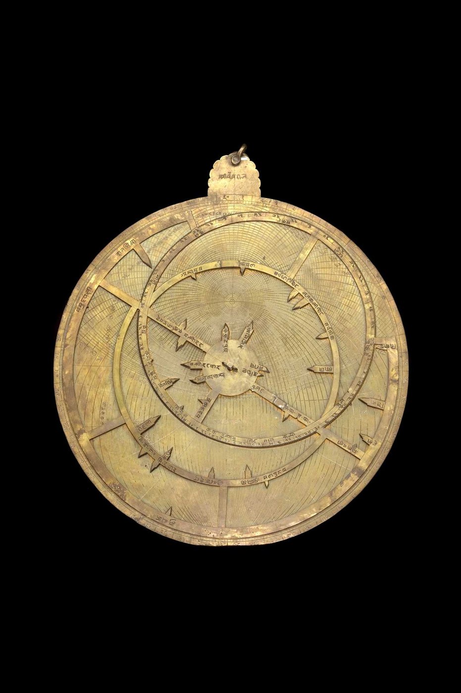 Full front view of the brass astrolabe showing the rete, throne with Sanskrit inscription, and the central pin and wedge.