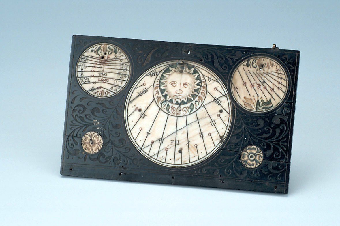 The interior side of the upper leaf, showing the central string gnomon dial and the two smaller pin gnomon dials at the top.