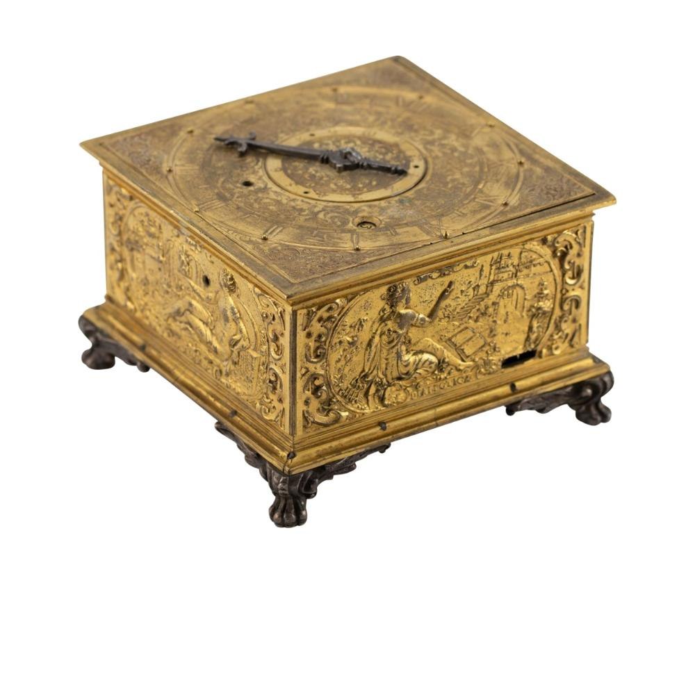 Elevated three-quarter view of the square firegilt horizontal table clock showing side relief panels and top dial