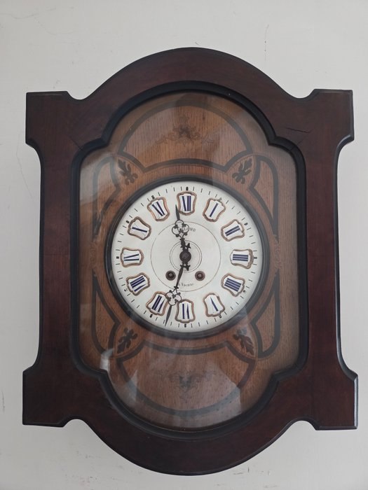 Front view of the French wooden wall clock showing the shaped case and dial through the glazed door