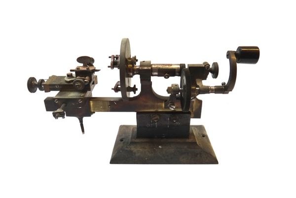 Side view of the brass and steel watchmaker's lathe on a rectangular base